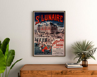 Wydruk plakatowy Bretania vintage – Saint-Lunaire, kąpiele morskie, oprawiony nad drewnianą komodą, między roślinami.