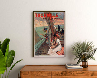 Plakat Normandie vintage – Trouville, Casino municipal, oprawiony nad drewnianą komodą, między roślinami.