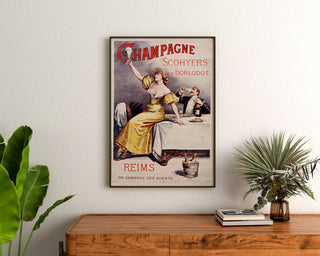 Retro plakat reklamowy Champagne Scohyers de Dorlodot, oprawiony nad drewnianą komodą, między roślinami.