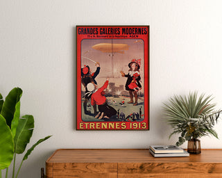Plakat reklamowy vintage Grandes Galeries modernes, Agen, w ramie nad drewnianą komodą, między roślinami.