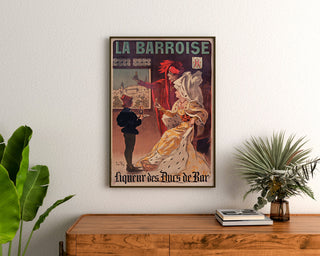 Retro plakat reklamowy La Barroise, oprawiony nad drewnianą komodą, między roślinami.