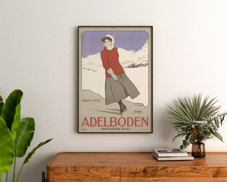 Szwajcarski plakat vintage – Adelboden – Carlo Pellegrini, 1905, oprawiony nad drewnianą komodą, między roślinami.
