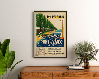 Turystyczny plakat vintage – Les Peupliers, kemping w Pont-de-Vaux, oprawiony nad drewnianą komodą, między roślinami.
