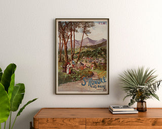 Plakat turystyczny vintage – Saint-Honoré-les-Bains, Tanconville, oprawiony nad drewnianą komodą, między roślinami.