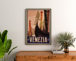 Wintage plakat turystyczny – Venezia, dzioby gondoli, oprawiony nad drewnianą komodą, między roślinami.