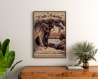 Wintage plakat Aix-les-Bains, grotte de Lamartine, w ramie nad drewnianą komodą, między roślinami.