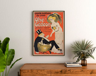 Plakat vintage Casino Kursaal, Ohé Gédéon, oprawiony nad drewnianą komodą między roślinami.
