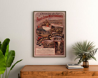Wydruk plakatowy vintage Dauphiné, wycieczki PLM, oprawiony nad drewnianą komodą, między roślinami.