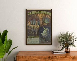 Plakat vintage Grottes de Bétharram, w ramie nad drewnianą komodą, między roślinami.