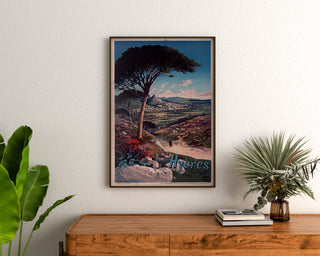 Vintage plakat Hyères, oprawiony nad drewnianą komodą między roślinami.
