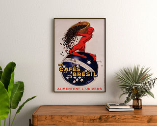 Plakat vintage Les Cafés du Brésil, w ramie nad drewnianą komodą, między roślinami.