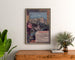 Plakat vintage Lourdes, kurorty nadmorskie, oprawiony nad drewnianą komodą między roślinami.