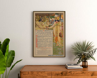 Plakat vintage Marseille, Fêtes du centenaire, oprawiony nad drewnianą komodą, między roślinami.