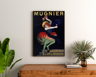 Vintage plakat Mugnier. Apéritif au vin de Bourgogne, oprawiony nad drewnianą komodą, między roślinami.