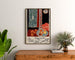 Plakat vintage Nice, Travail et Joie, oprawiony nad drewnianą komodą, między roślinami.