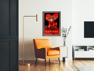 Wintage plakat Rapidol, oprawiony w salonie obok pomarańczowego fotela i lampy stojącej.