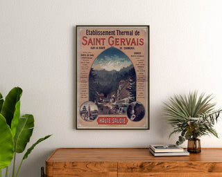 Plakat vintage Saint-Gervais, uzdrowisko, oprawiony nad drewnianą komodą, między roślinami.