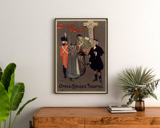 Plakat vintage Shamus O’Brien, Opera Comique, oprawiony nad drewnianą komodą, między roślinami.