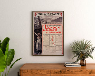 Plakat vintage South Eastern, England-France, oprawiony nad drewnianą komodą, między roślinami.