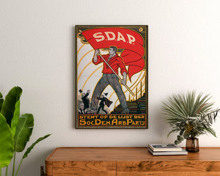 Plakat vintage Stemt SDAP, wybory, oprawiony nad drewnianą komodą, między roślinami.