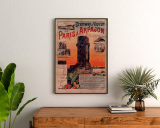 Plakat vintage Tramway Paris-Arpajon, oprawiony nad drewnianą komodą, między roślinami.