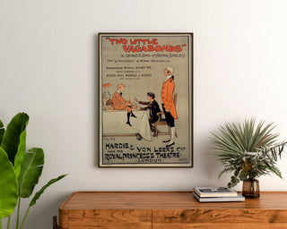 Plakat vintage Two Little Vagabonds, oprawiony nad drewnianą komodą, między roślinami.